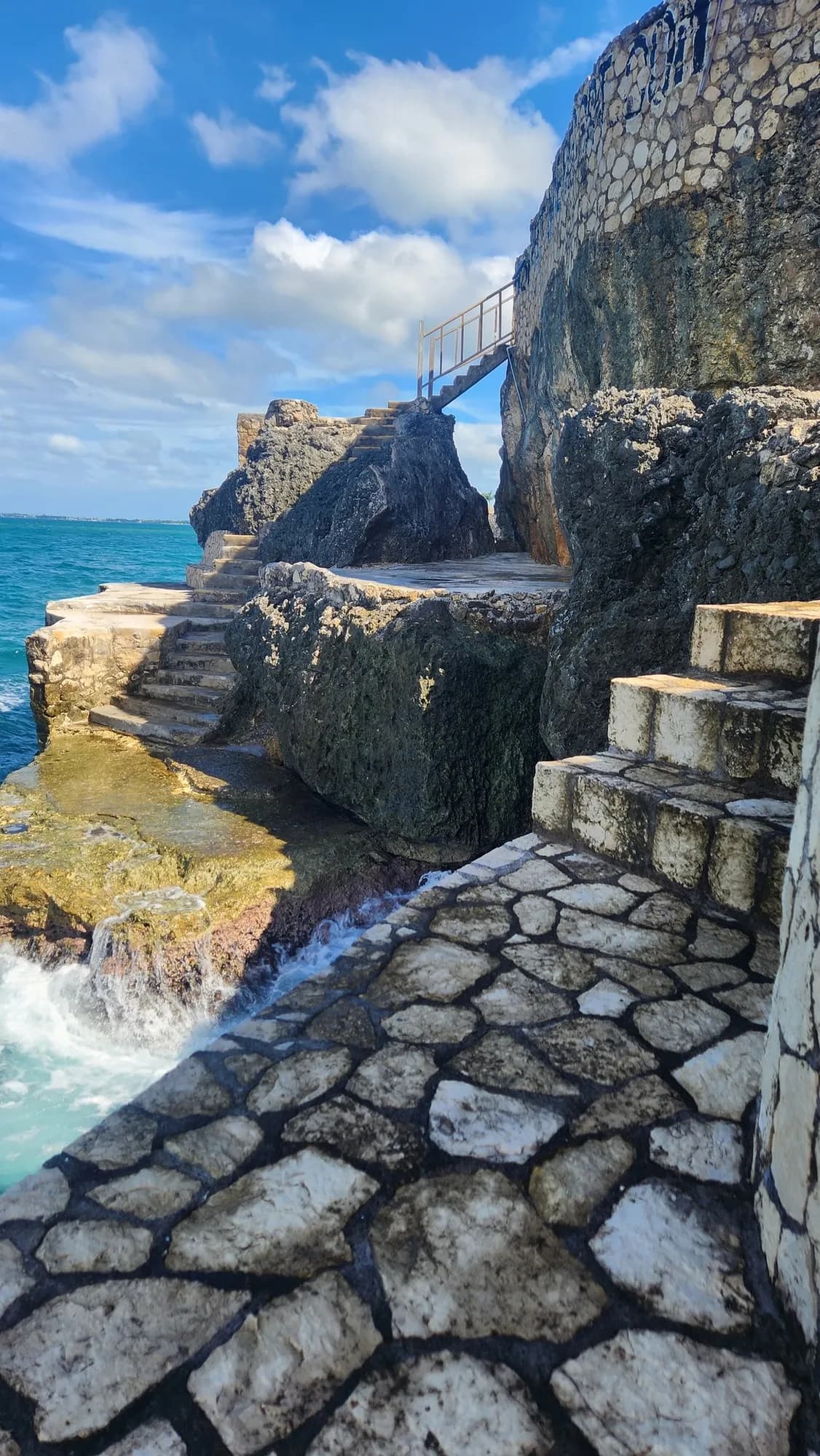 Stone steps with a rail leading down the cliff into the sea