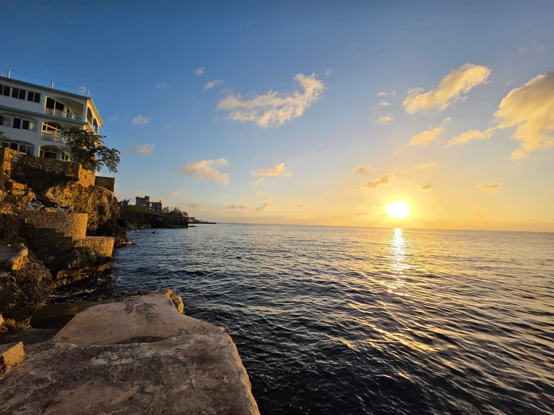 The sun setting into the sea off the cliffs, the resort to the left