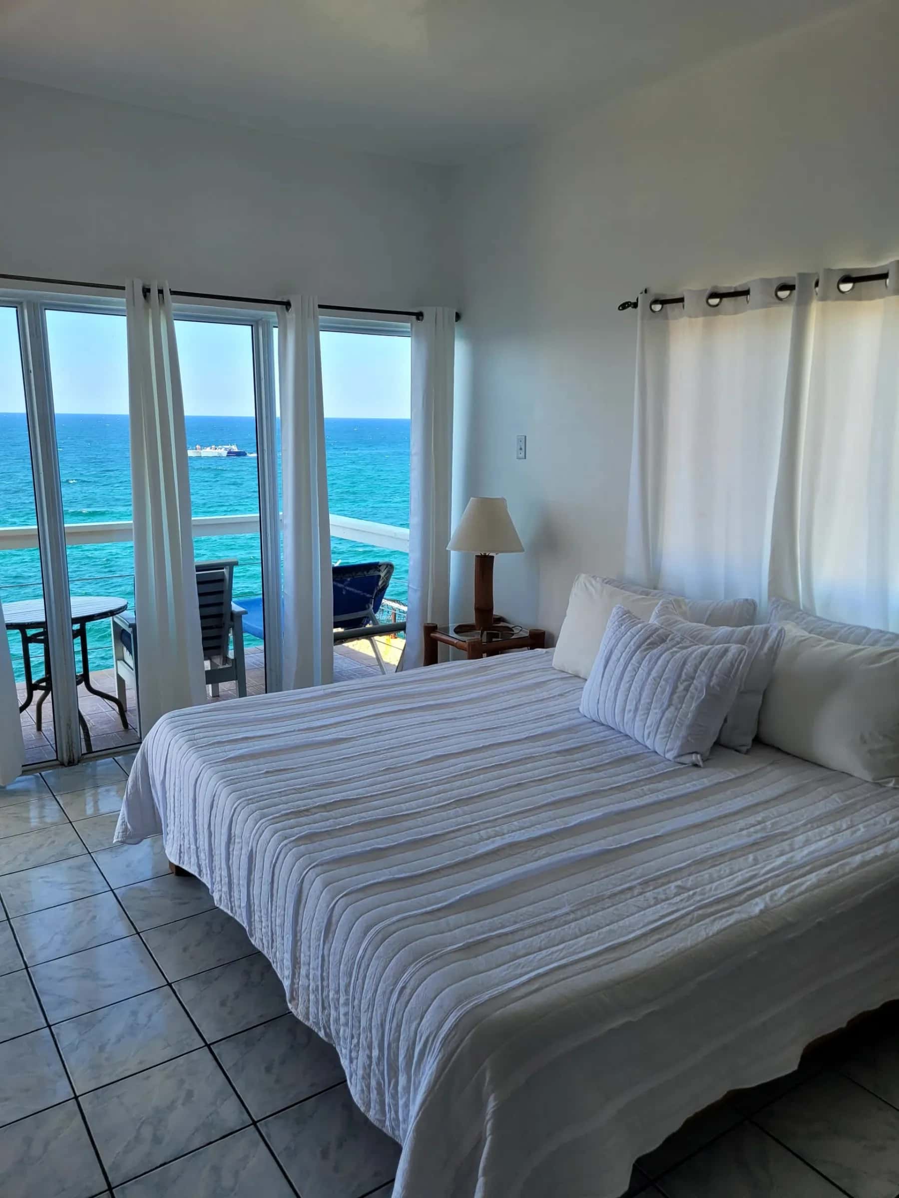 King bed facing a wall of windows that opens to the Caribbean Sea in the Cliffedge Suite, Room 16