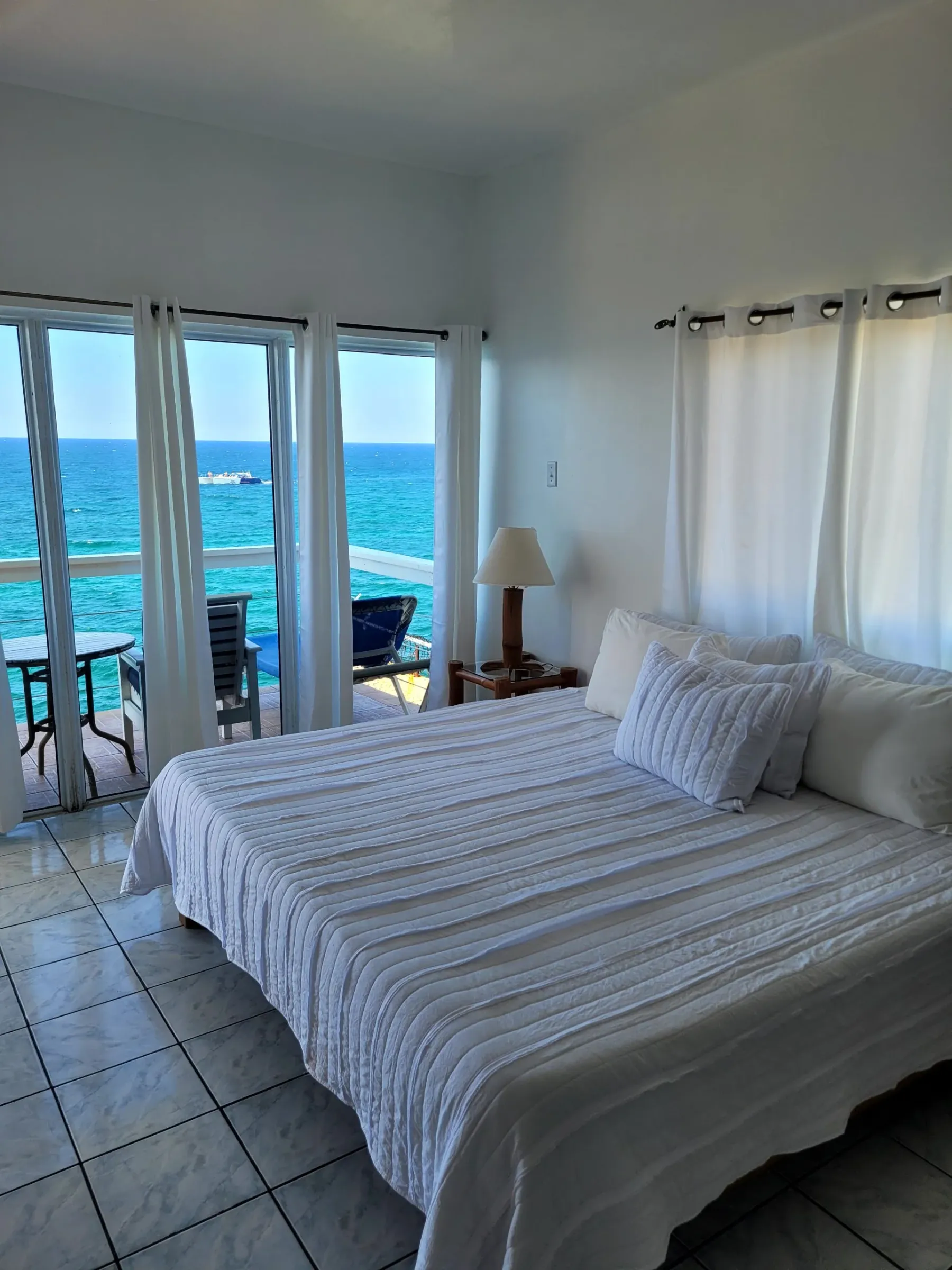 King bed facing a wall of windows that opens to the Caribbean Sea in the Cliffedge Suite, Room 16