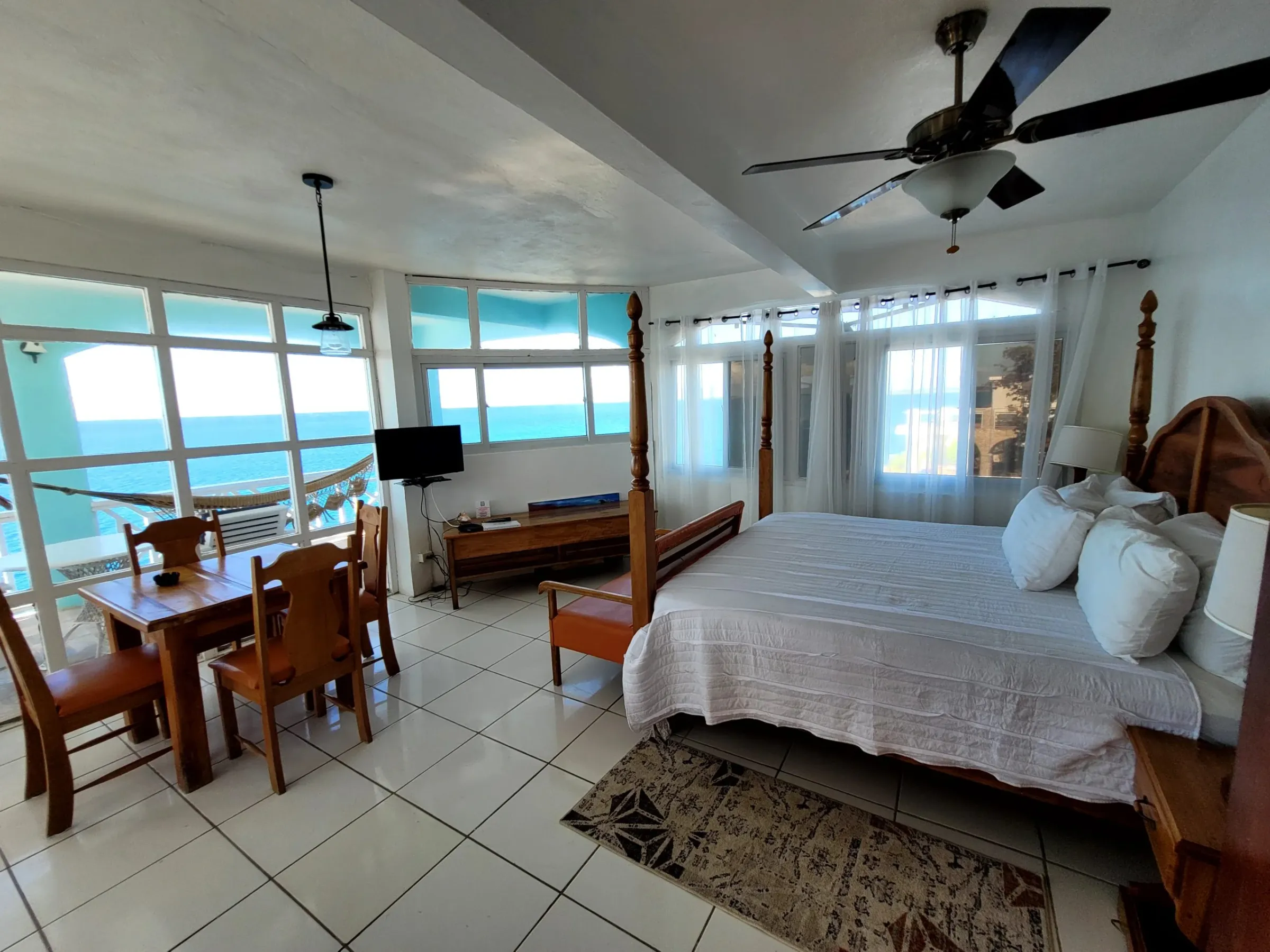 Four-poster king bed with wraparound windows over the Caribbean Sea in the Original Penthouse, Room 12