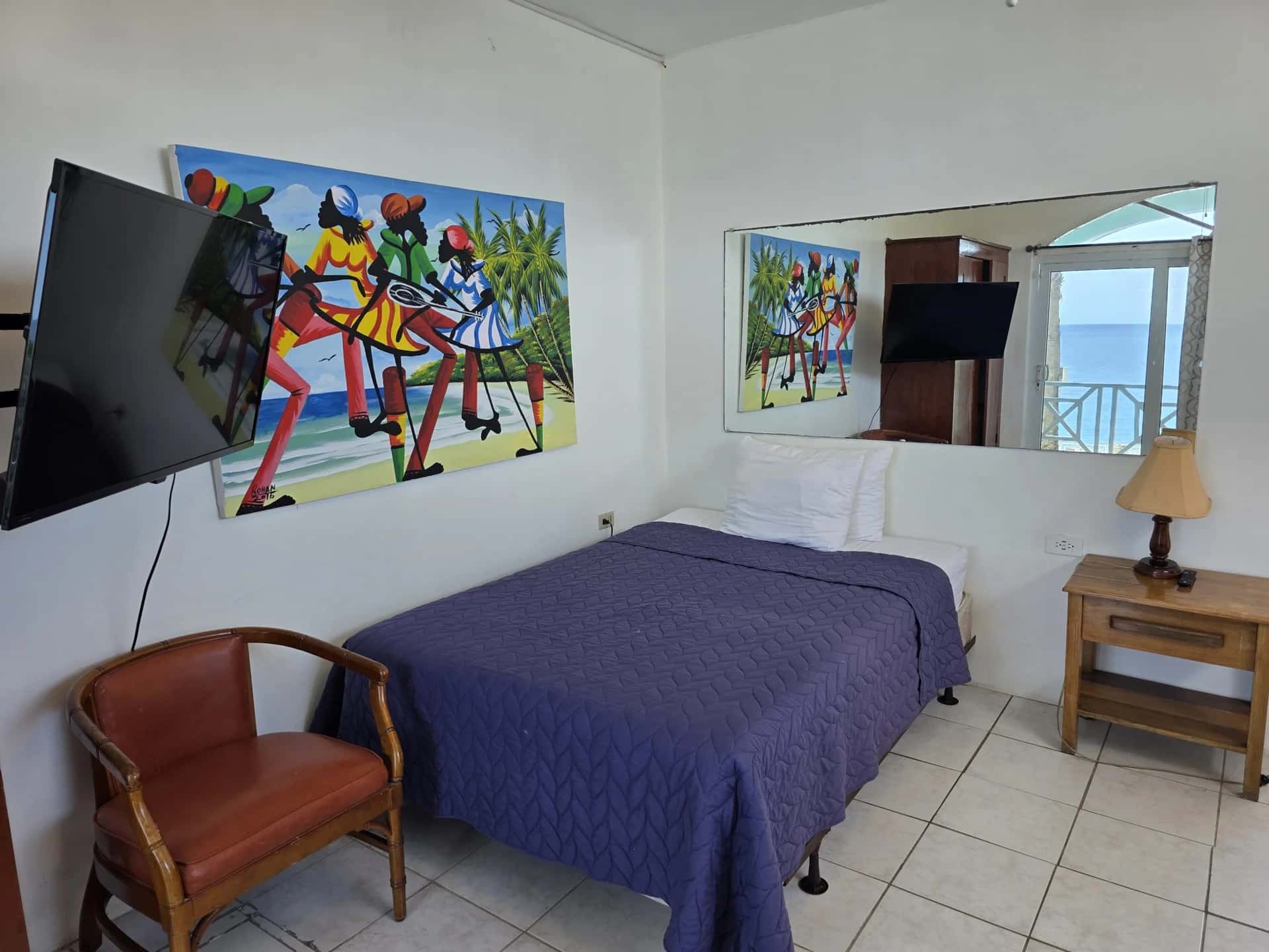 Two double beds with a sea-view window and local artwork in Seaview Deluxe Room 4