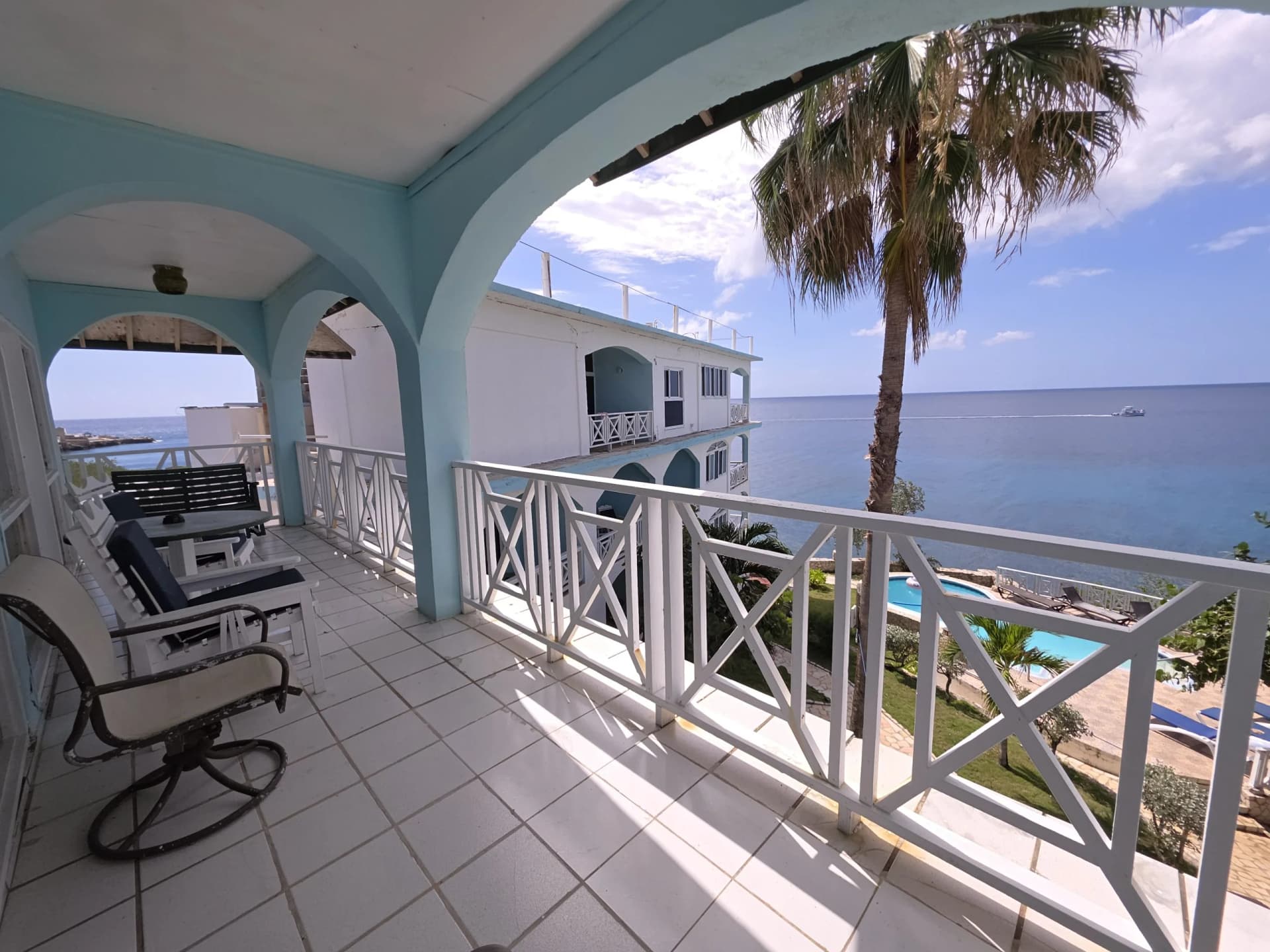 Spacious private balcony with seating overlooking the Caribbean Sea and the cliffside pool in the Sunset Suite, Room 14